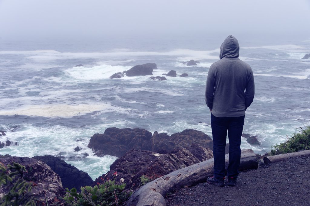 Man standing on an overlook near the ocean contemplating life, representing living with depression. Life can be more than shades of gray. Bring back the color with depression treatment in Arizona today. 