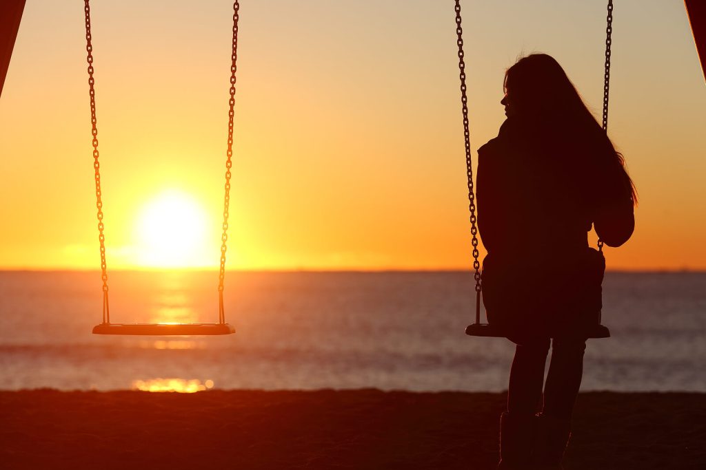 Woman sitting alone on a swing framed by the sunset representing someone who is in need of support to face the challenges that come with Adult ADHD. Online ADHD Treatment in Arizona is available to help!