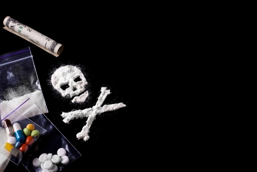 Illicit drugs sitting on a counter with the skull and crossbones representing the negative aspects of substance abuse. Overcome your addiction with Medically-Assisted Detox in Arizona.